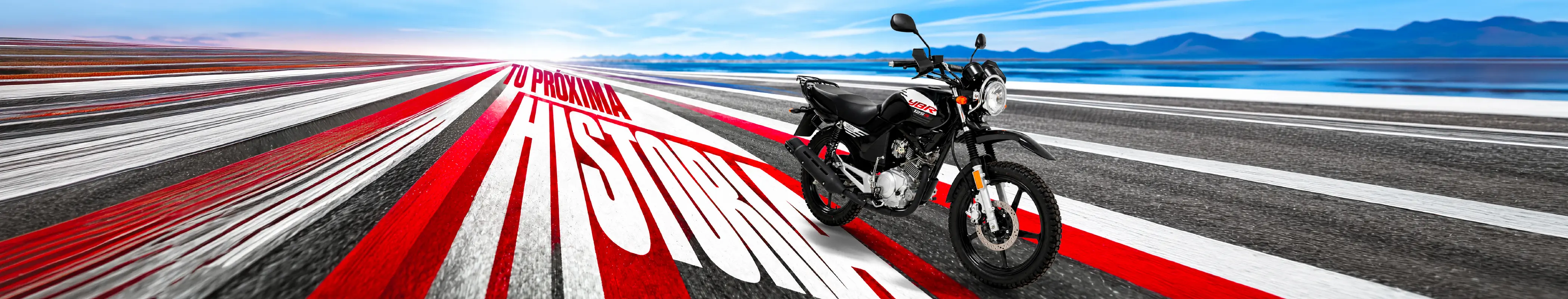 Tu próxima historia: una Yamaha YBR 125G negra sobre una pista de franjas rojas y blancas, con el lago y las montañas al fondo